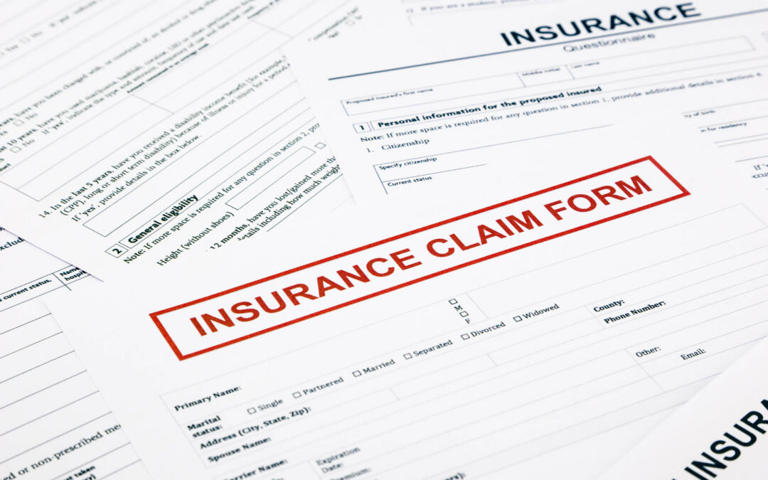 A close-up of several white insurance documents, highlighting a form with "INSURANCE CLAIM FORM" printed in bold red letters within a red box - https://www.staplesagency.com/