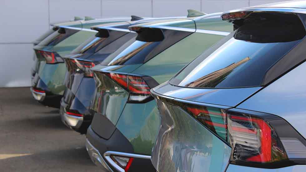 The rears of a fleet of green and gray hatchbacks used for business purposes - staplesagency.com