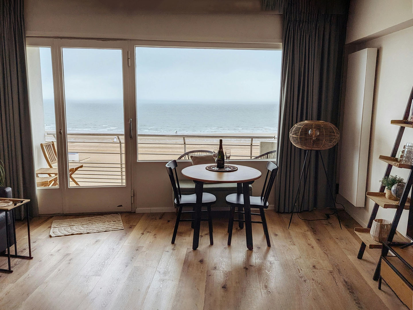 Inside a beachfront condo looking through living room window, past the balcony to the ocean beyond.
